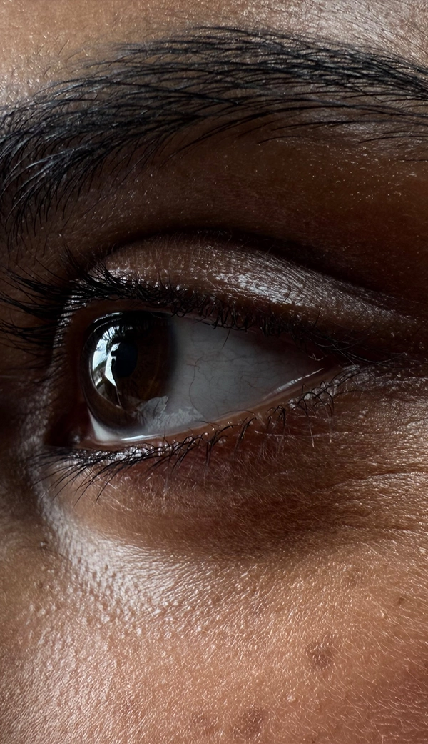 Женщина фотографируется в пустой комнате. Боковое лицо женщины увеличено, акцент сделан на глазах. Приложение «Фото» переключает фокусные расстояния, чтобы продемонстрировать возможности профессиональной камеры: макросъемка.